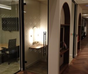 Ceiling-mounted sound masking speaker inside a glazed work booth, designed for discreet noise control and privacy enhancement.