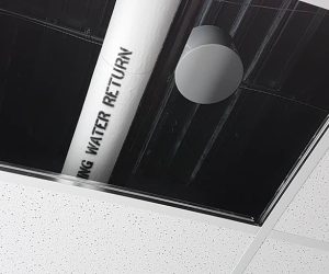 "Close-up of a sound masking speaker partially visible above ceiling tiles, showing its placement within the plenum space for overhead noise distribution.